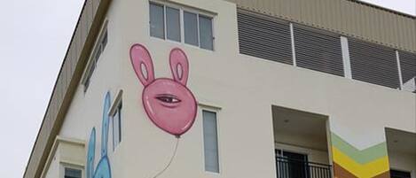 Un edificio de varios pisos con un mural colorido de personajes de caricatura en la pared exterior.