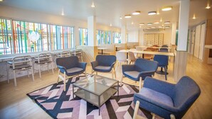Un espace de détente moderne, doté de sièges confortables, d’une table basse et de grandes fenêtres.