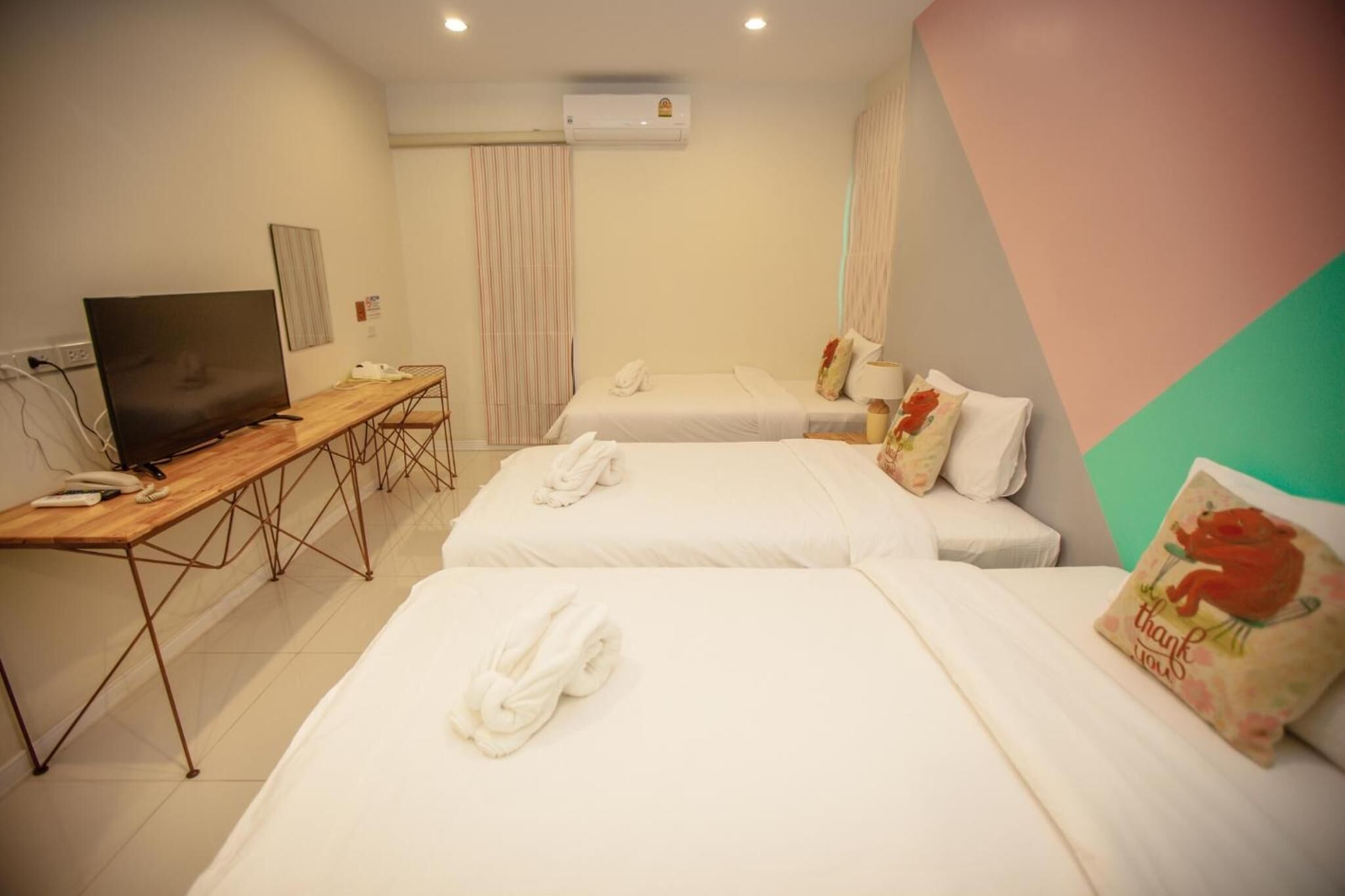 Habitación de hotel con dos camas, un escritorio con televisor y un equipo de aire acondicionado.