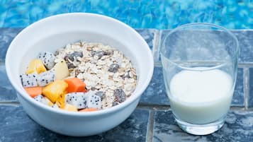 Un tazón de cereal con frutas y un vaso de leche junto a una piscina.