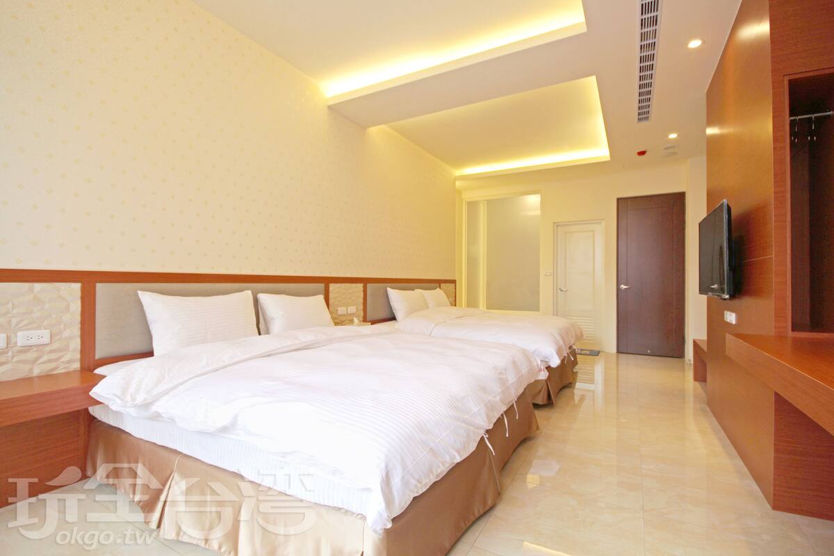 A hotel room with a large bed, a TV, and a wooden desk.