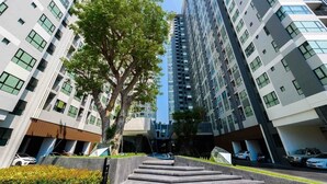 Un moderno edificio de gran altura con un árbol central y una escalera que lleva a una entrada.