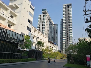 Un quartier urbain moderne, avec de grands immeubles résidentiels, une entrée sécurisée et un ciel dégagé.