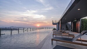 Un edificio moderno con piscina en la azotea y vistas a la puesta de sol.