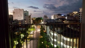 Une vue sur la ville, prise depuis un balcon, avec des immeubles, une route et quelques espaces verts.