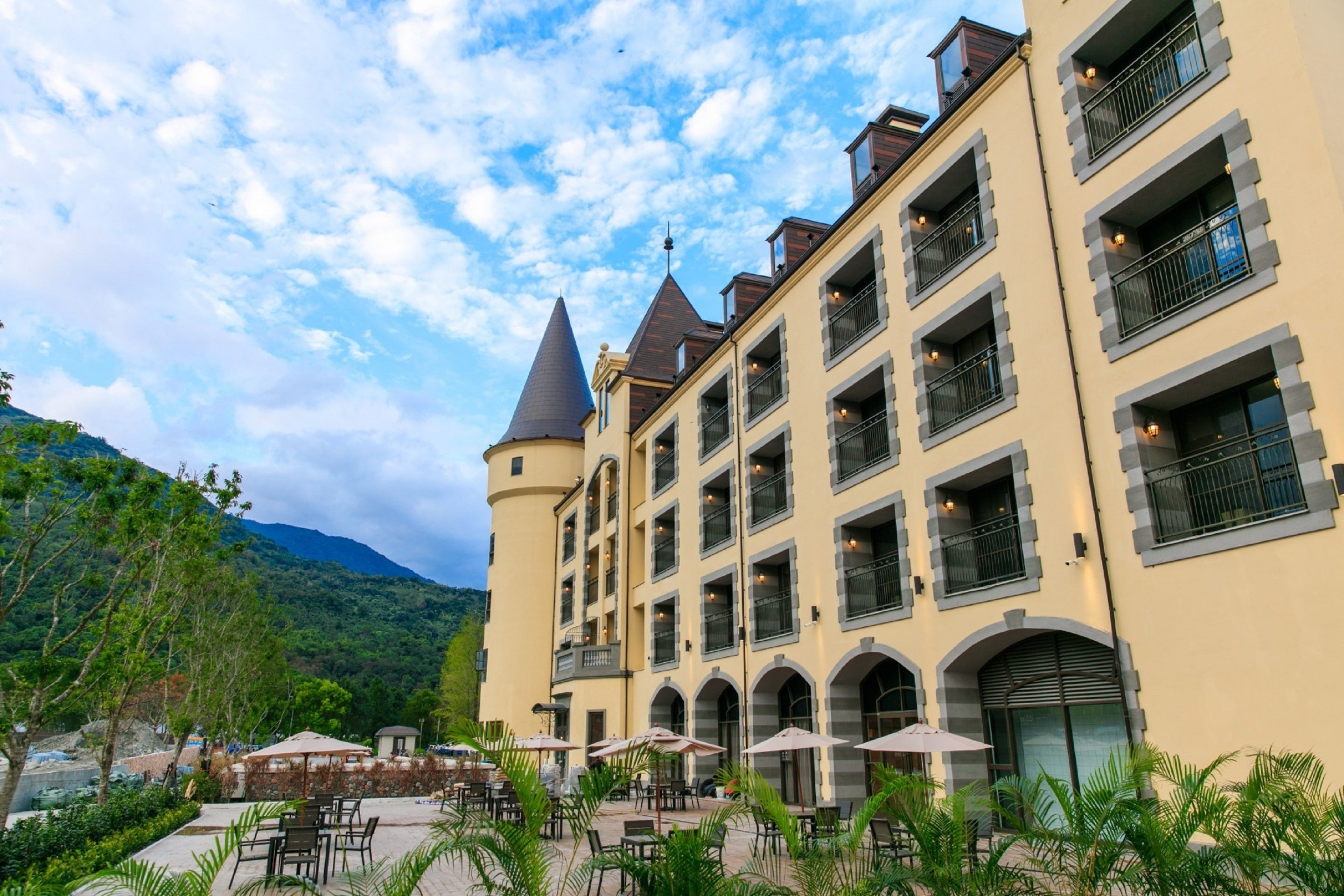 Un hôtel à plusieurs étages doté d’une cour intérieure aménagée avec des espaces de détente en plein air et offrant une vue sur les montagnes.