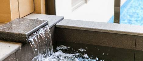 A water feature with a stone ledge and a pool in the background.