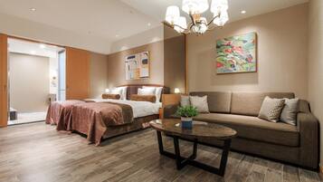 A modern hotel room with a bed, a sofa, a coffee table, and a chandelier.