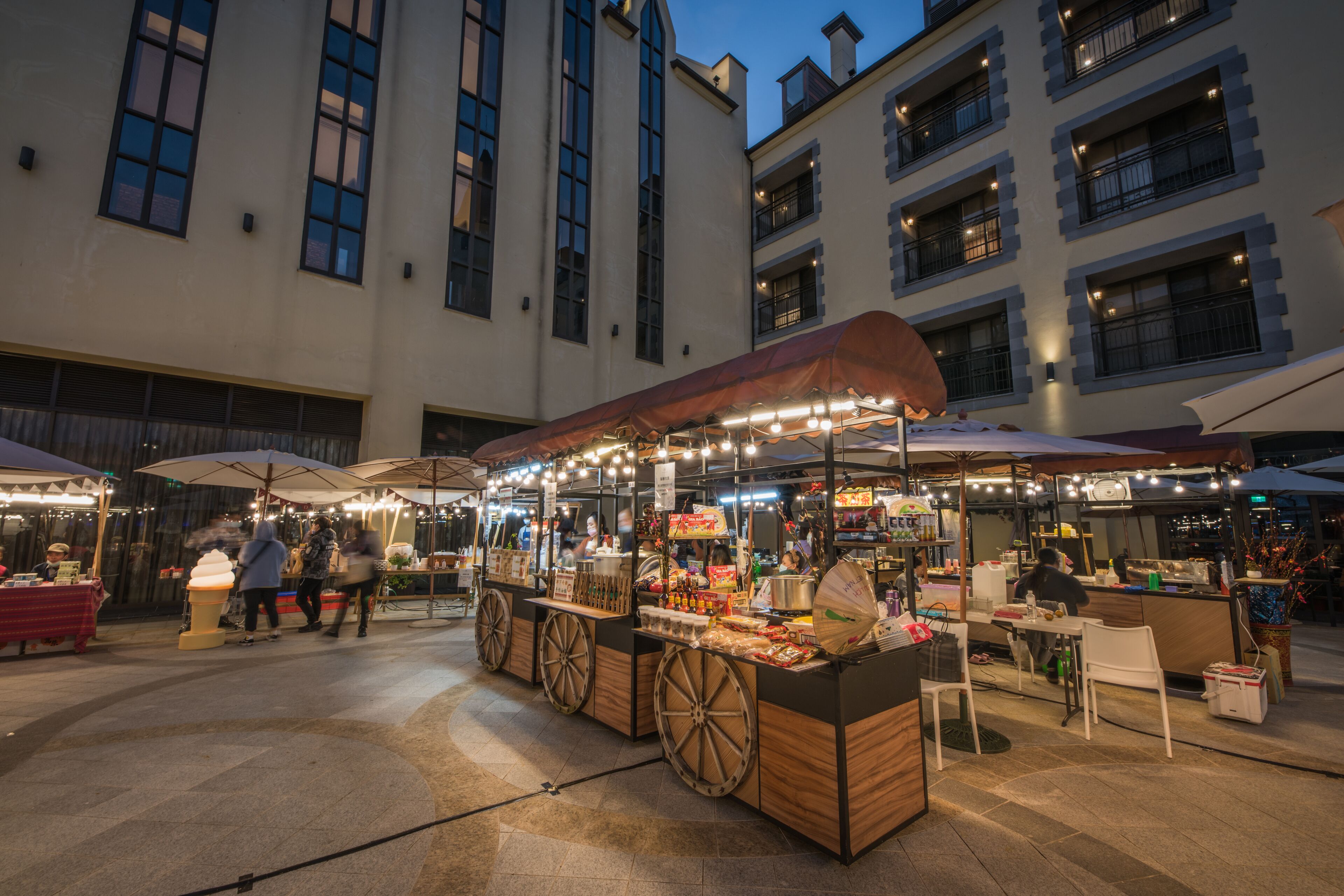 Un marché en plein air avec des stands de nourriture et des espaces aménagés pour s’asseoir.