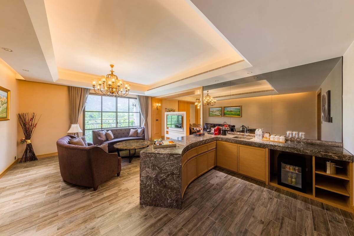 A modern kitchen with a marble island, built-in appliances, and a seating area with a sofa and a dining table.