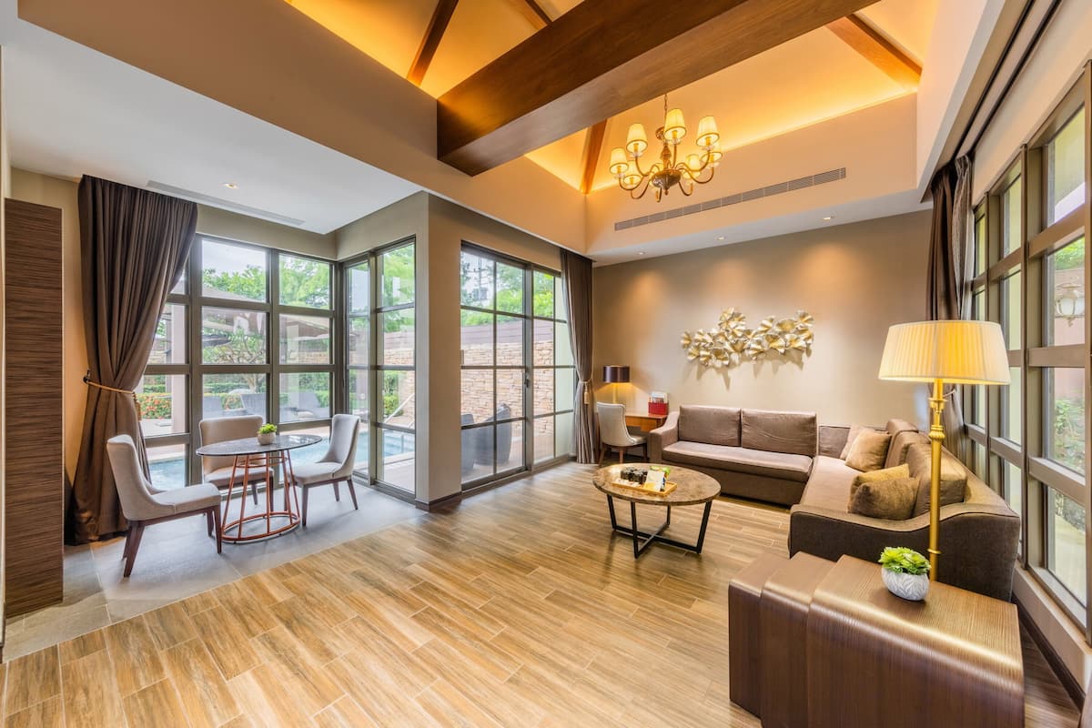 A spacious living area with a wooden floor, a sofa set, a coffee table, and a chandelier.