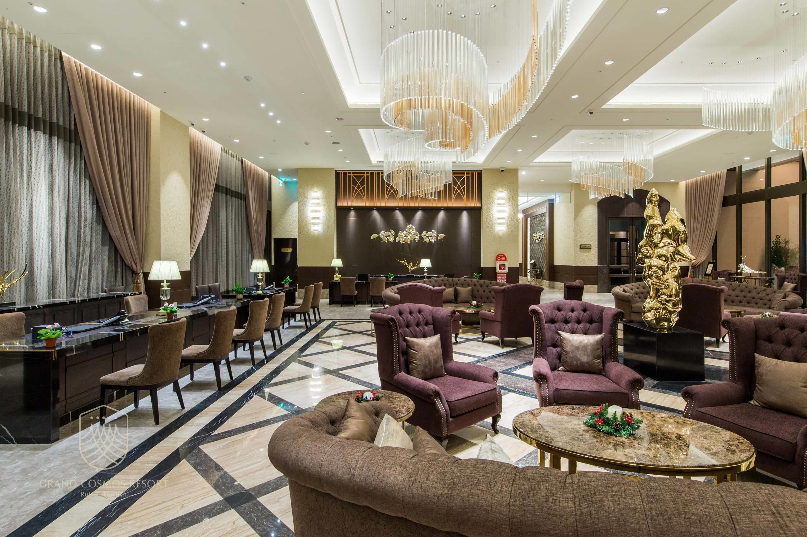 A spacious lobby with a marble floor, plush seating, and a large chandelier.