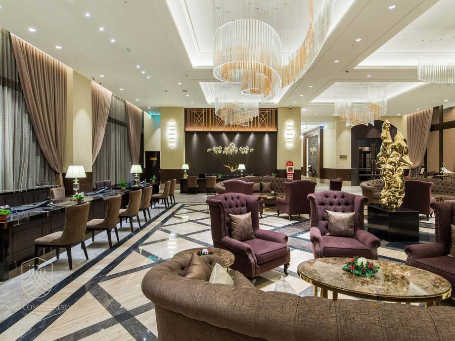 A spacious lobby with a marble floor, plush seating, and a large chandelier.