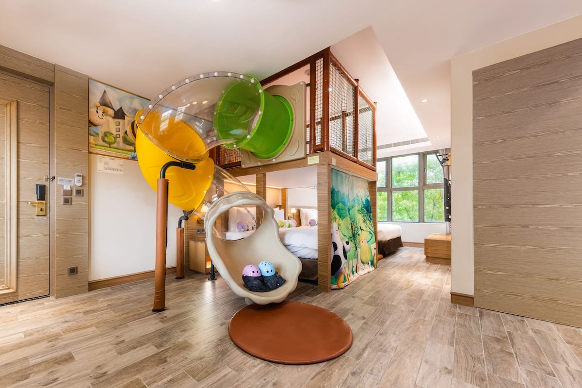 A children's play area with a slide, a hanging chair, and a playpen.