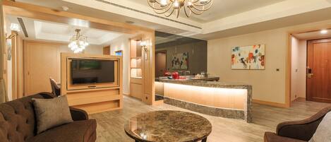 A modern living room with a TV, a round coffee table, and a chandelier.
