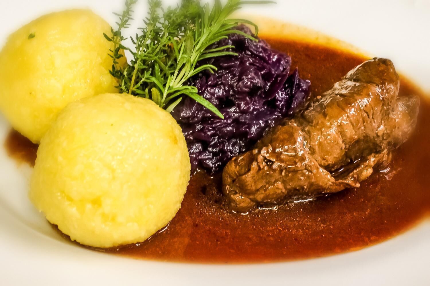 Un plato con carne, puré de papas y col roja.