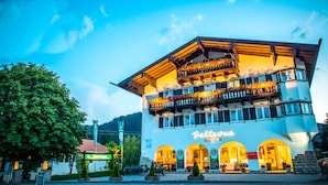Ein Hotel mit Balkon, der mit Blumen geschmückt ist, einem Schild mit der Aufschrift "Bellerive Hotel" und Blick auf die Umgebung, darunter ein Restaurant und ein Schild für "Bainhaus".