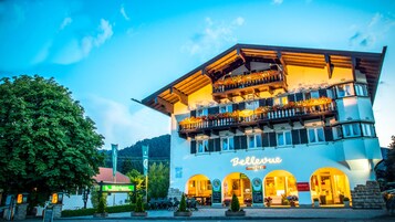 Un hotel con un balcón decorado con flores, un cartel que dice "Bellerive Hotel" y vistas del entorno, incluyendo un restaurante y un letrero que indica "Bainhaus".