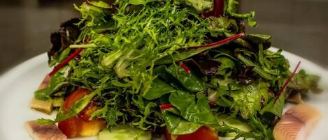 Ensalada de hojas verdes variadas con tomates y rodajas de pepino.
