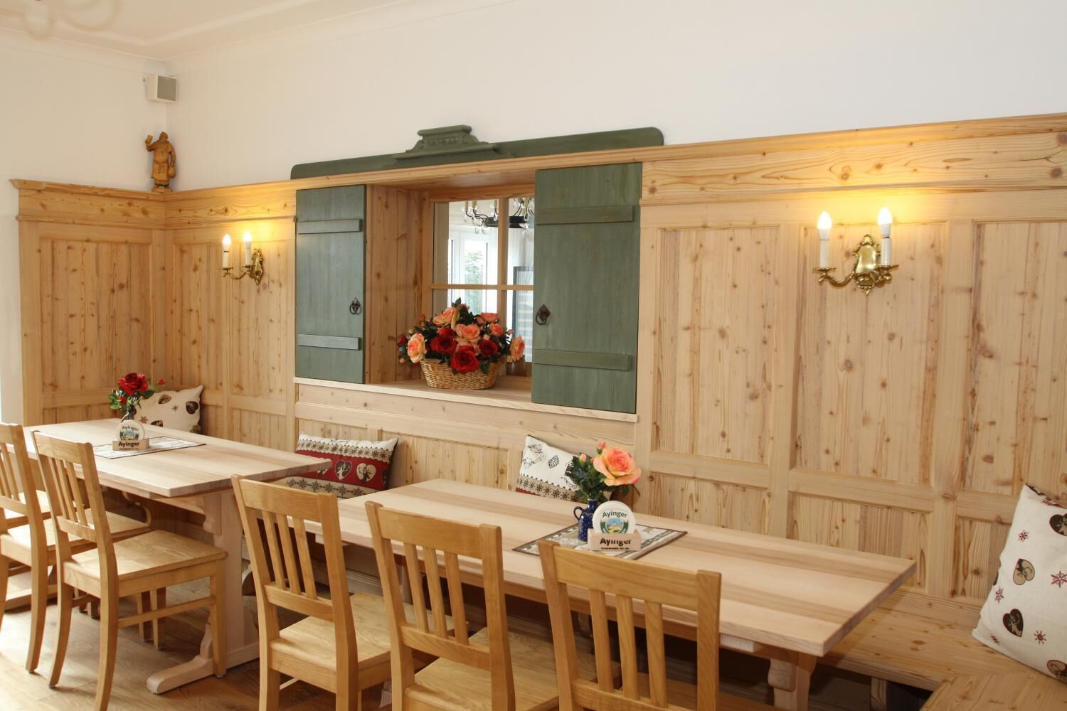 En matplats med träinredning, ett långt bord och stolar, en spegel ovanför bordet och ett fönster med en blomkruka.
