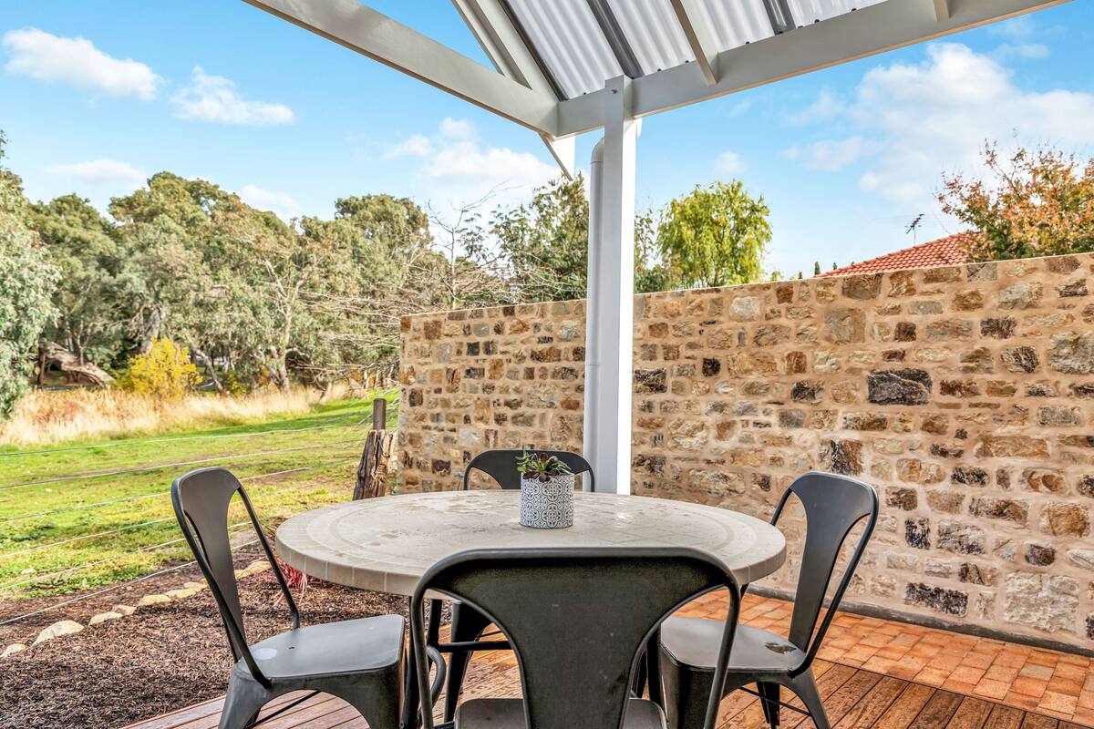 An outdoor patio with a stone wall, a round table, and four chairs.