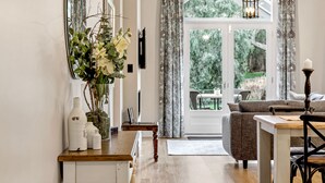 A modern living room with a sofa, a dining table, and a large window with curtains. - Grandview Accommodation - The Elm Tree Apartments (Mount Barker)