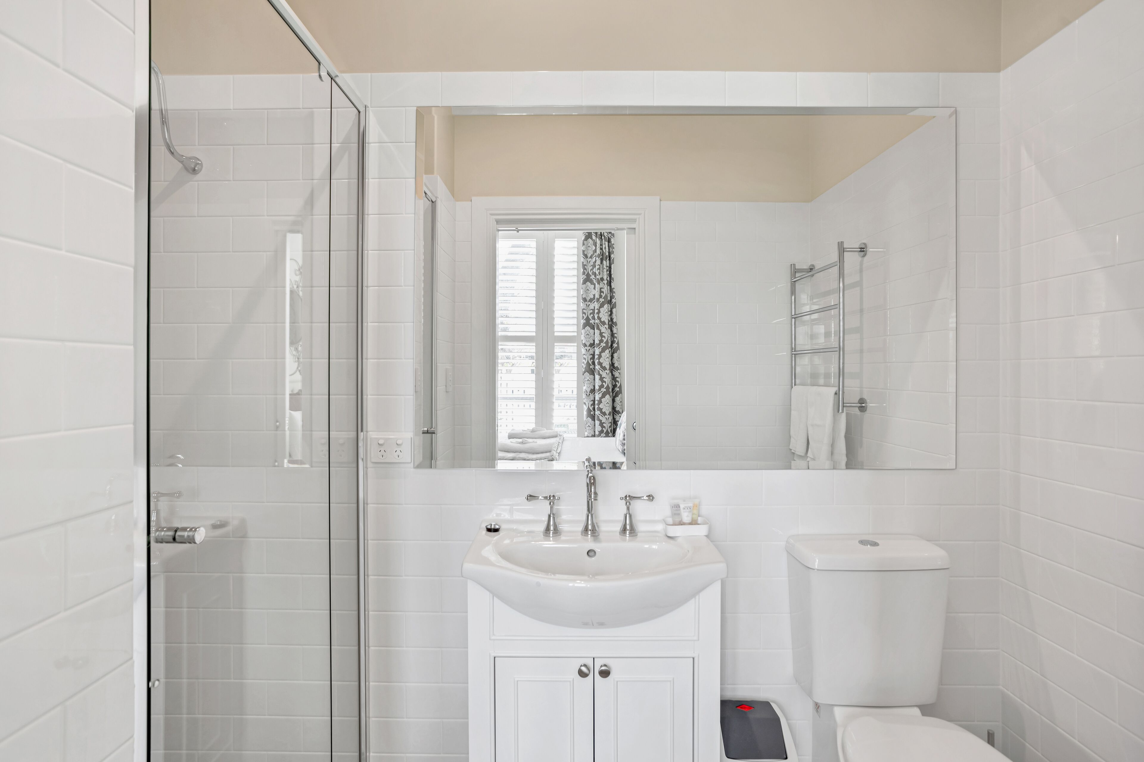 A modern bathroom with a glass shower enclosure, a white sink with a mirror above, and a toilet.