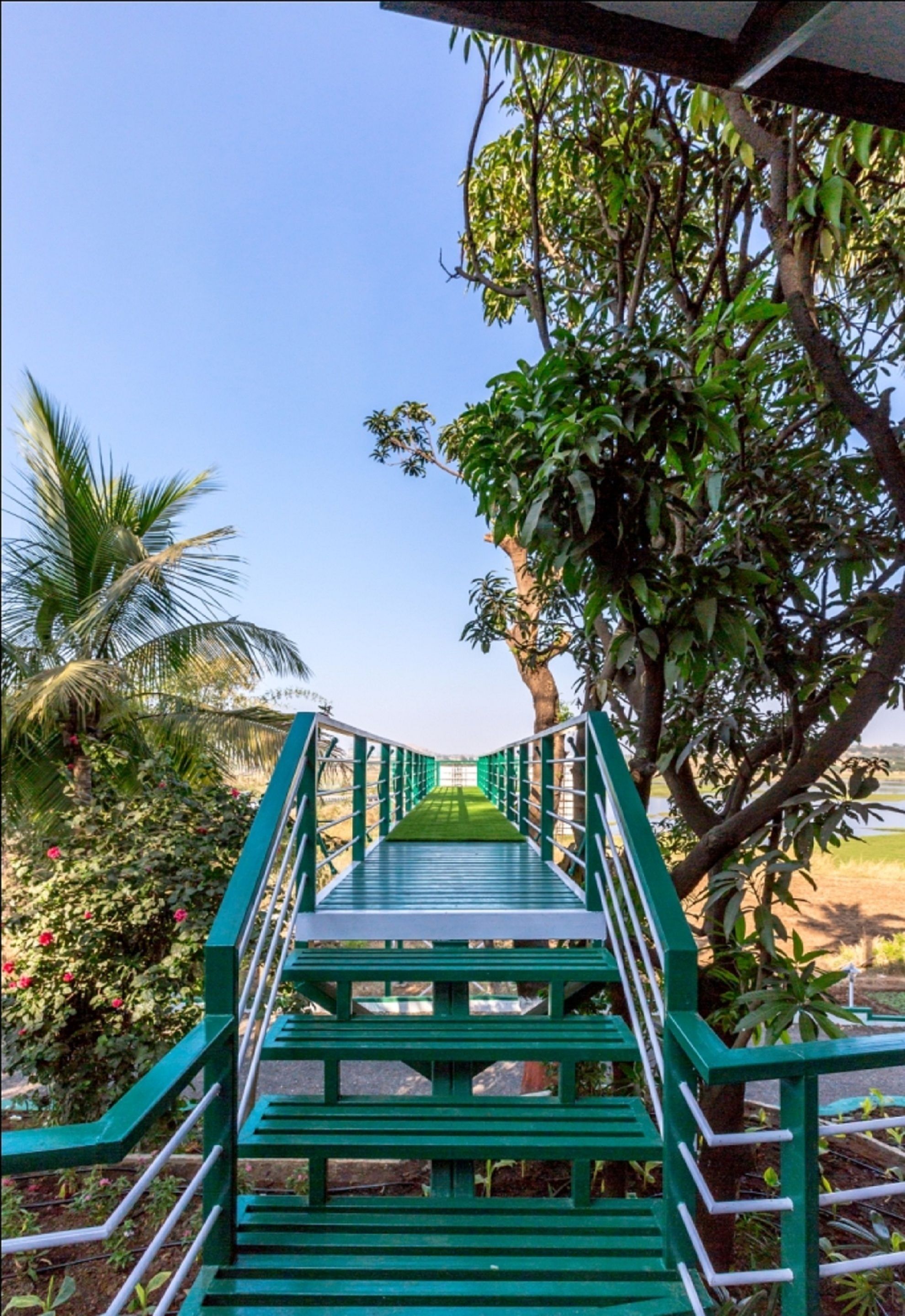 Un puente de madera verde con barandillas que conduce a un área techada.