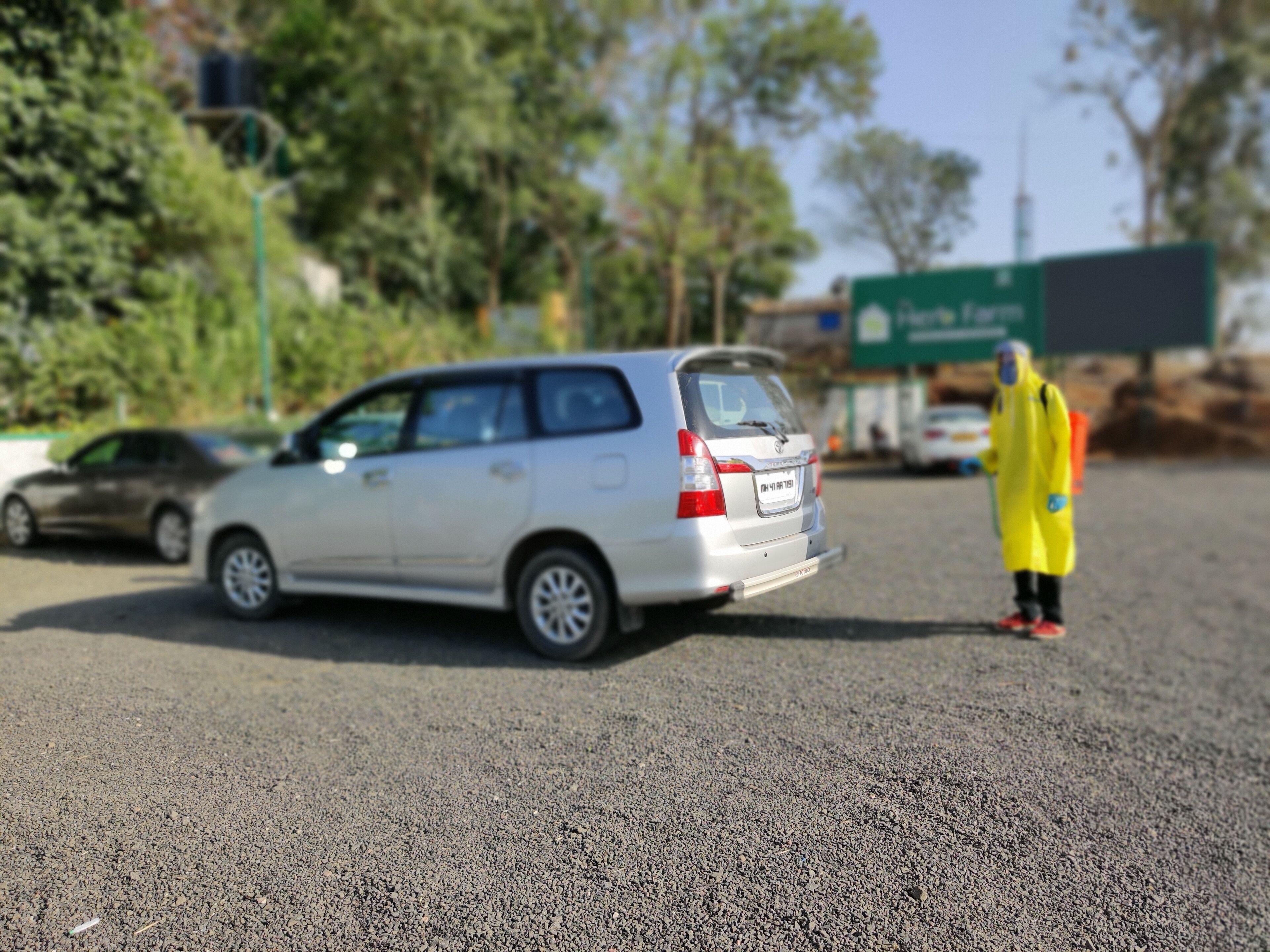 A model car and a figure in a yellow suit on a gravel surface.