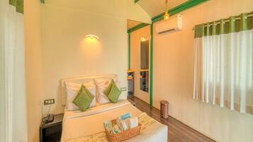A hotel room with a bed, bedside table, and a window with curtains.