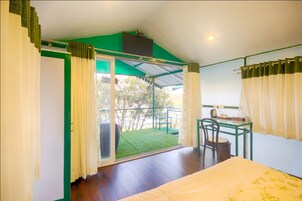 Una habitación con cama, escritorio y vista a un espacio exterior verde.