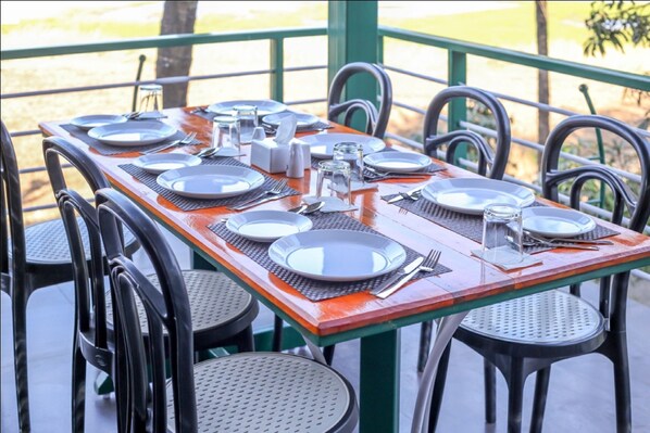 Una mesa de comedor dispuesta con platos, cubiertos y vasos, rodeada de sillas.