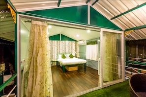 A bedroom with a bed, a green wall, and a sliding glass door. - The Herb Farm (Igatpuri)