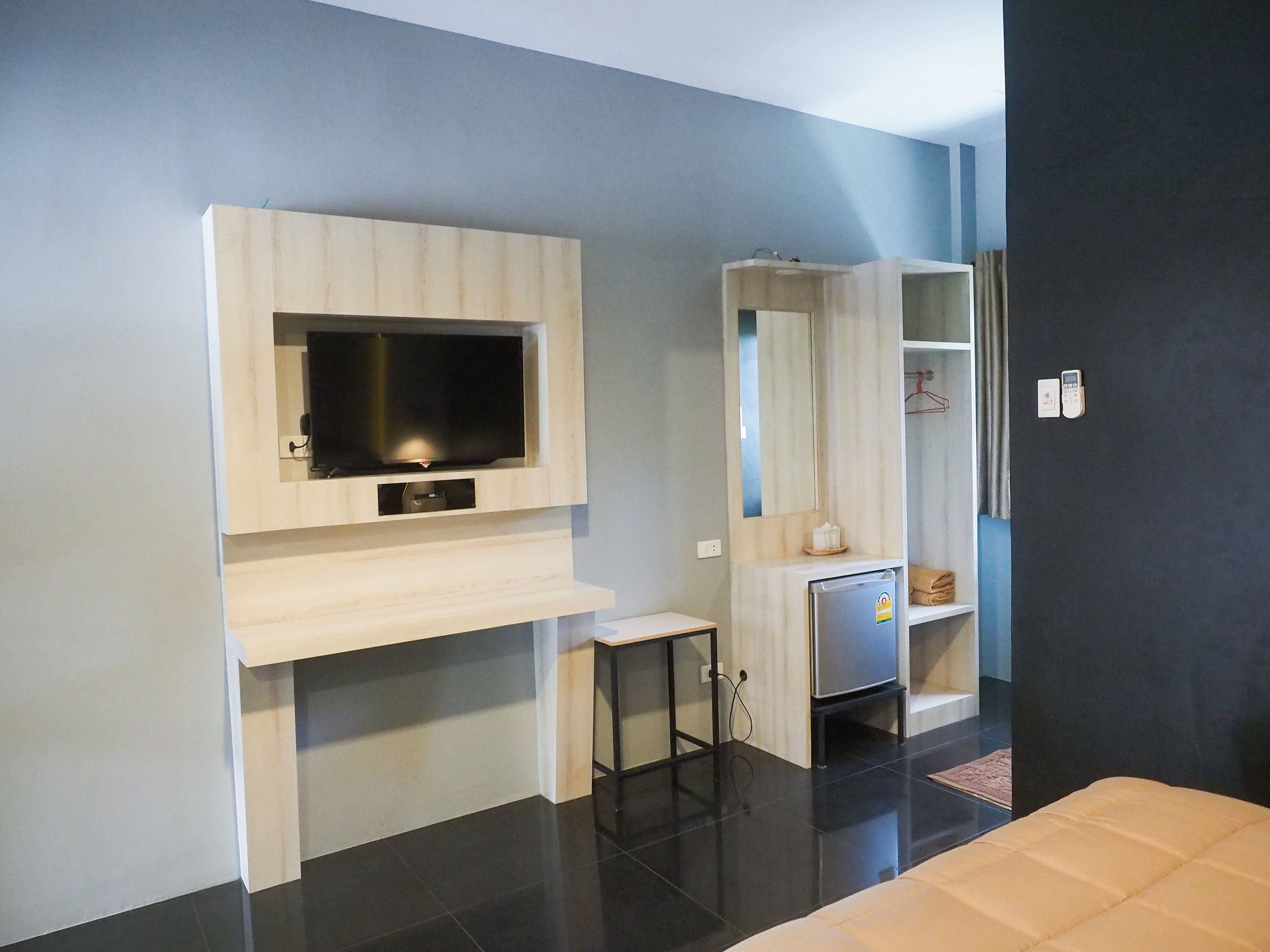 A modern room with a flat-screen TV mounted on a light-colored wall, a small table, a built-in shelf, and a dark-colored wall.