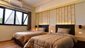 Habitación de hotel con dos camas, un equipo de aire acondicionado, una ventana con cortinas y un estante fijado a la pared.