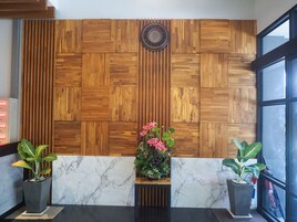 Un área de recepción con un diseño de paneles de madera, suelo de mármol y plantas en macetas.