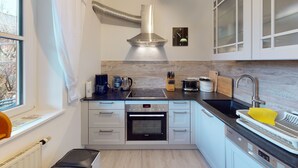 A modern kitchen with a built-in oven, a coffee maker, and a sink with a drying mat. - Ferienwohnung für 1-2 Pers., ca. 49 m²,  1 Schlafzimmer, Wohnraum, Terrasse (Bischofswiesen)