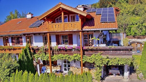 A two-story wooden house with a balcony, solar panels, and a garden. - Ferienwohnung für 1-2 Pers., ca. 49 m²,  1 Schlafzimmer, Wohnraum, Terrasse (Bischofswiesen)