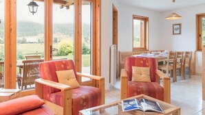 A cozy room with wooden furniture, large windows, and a view of the countryside. - Family 4-room apartment, terrace, near slopes (Le Monêtier-les-Bains)