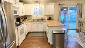 A kitchen with white cabinets, stainless steel appliances, a wooden countertop, and a view to the outside. - Comfortable/Cozy Home (American Fork)