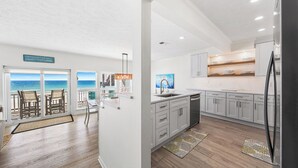 A modern kitchen with white cabinets, a stainless steel refrigerator, and a view of the ocean through large sliding glass doors. - 2 Beach Sets ☀️ Beachfront Ocean View | Private Beach | Direct Access ☀️ 118 10-Star Reviews (Santa Rosa Beach)