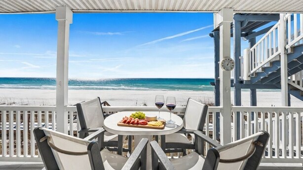 A covered outdoor seating area with a table set for two, overlooking a beach. - 2 Beach Sets ☀️ Beachfront Ocean View | Private Beach | Direct Access ☀️ 118 10-Star Reviews (Santa Rosa Beach)