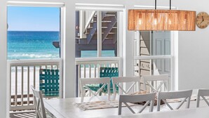 A dining area with a view of the ocean, white furniture, and a hanging copper pendant light. - 2 Beach Sets ☀️ Beachfront Ocean View | Private Beach | Direct Access ☀️ 118 10-Star Reviews (Santa Rosa Beach)
