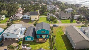 A residential area with houses, a beach, and a hill in the background. - Aoy Matey · Cute family home, close to beach, fenced yard (Cloverdale)