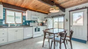 A kitchen with white cabinets, a wooden ceiling, and a dining table with chairs. - Aoy Matey · Cute family home, close to beach, fenced yard (Cloverdale)