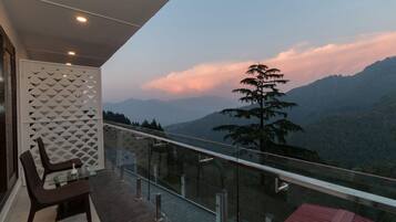 A balcony with a glass railing overlooking a mountainous landscape.
