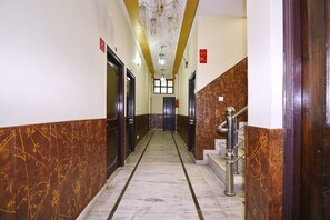 A hallway with marble flooring, wooden doors, a staircase, and a chandelier. - OYO 4069 Morning Star (Dehradun)