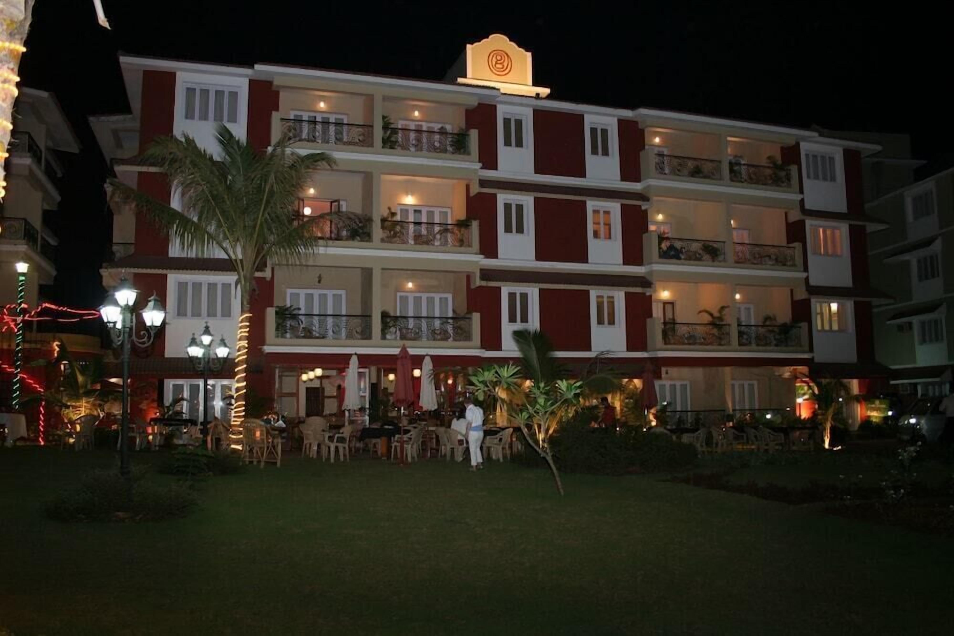 A multi-story hotel with balconies, outdoor seating, and a well-lit entrance.