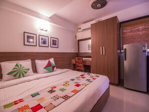 A hotel room with a bed, a desk, a chair, a wardrobe, and a refrigerator. - OYO 11443 Home Exotic Studio Panjim (Panaji)