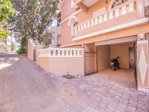 A residential building with a gated entrance, a parked motorcycle, and a paved driveway. - OYO 11443 Home Exotic Studio Panjim (Panaji)